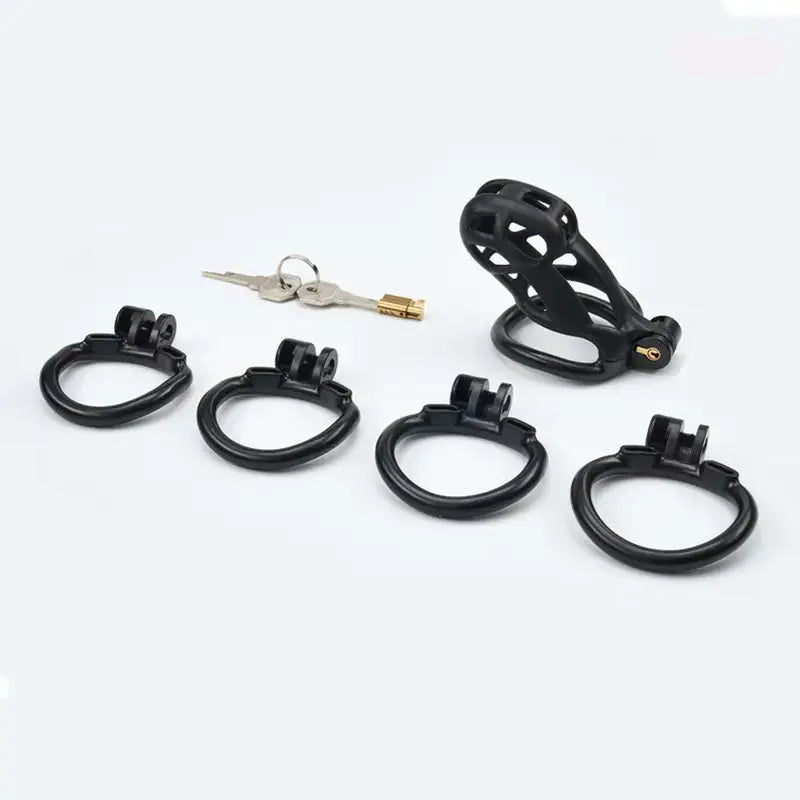 Set of black metal rings with 2 keys and a cobra chastity cage on a white background